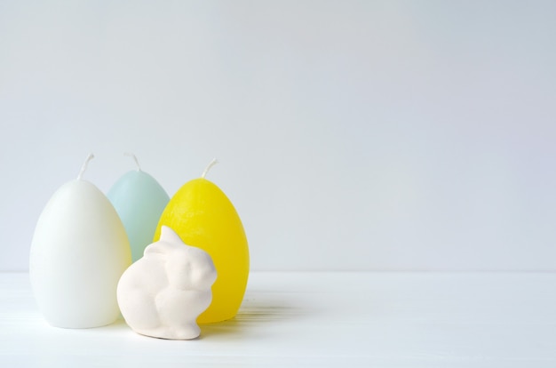 Easter  bunny with egg shaped candles on white  with copyspace