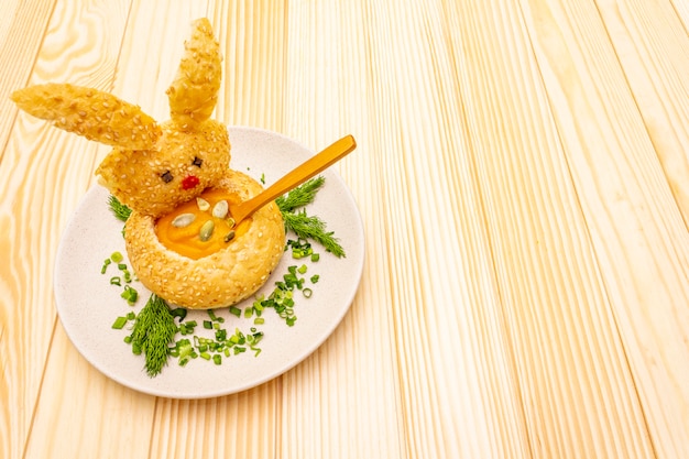 Easter bunny with warm pumpkin cream soup with herbs and pumpkin seeds