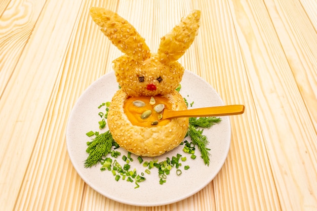 Easter bunny with warm pumpkin cream soup with herbs and pumpkin seeds