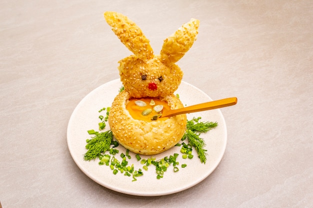 Easter bunny with warm pumpkin cream soup with herbs and pumpkin seeds