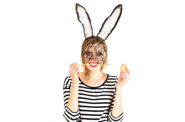 Photo easter bunny woman painting egg sexy girl in rabbit mask with paint brush in mouth decorating eggs