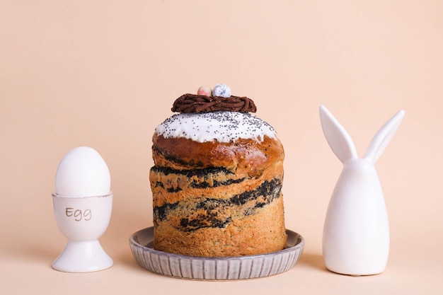 Easter cake and bunny figurine on beige paper background