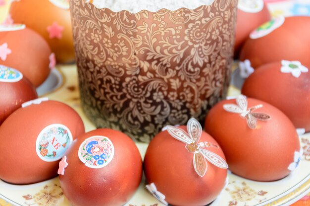 Easter cake and decorated chicken eggs laid out on a plate. Easter tradition: chicken eggs are exchanged and they say: "Jesus is Risen!" Easter celebrations.