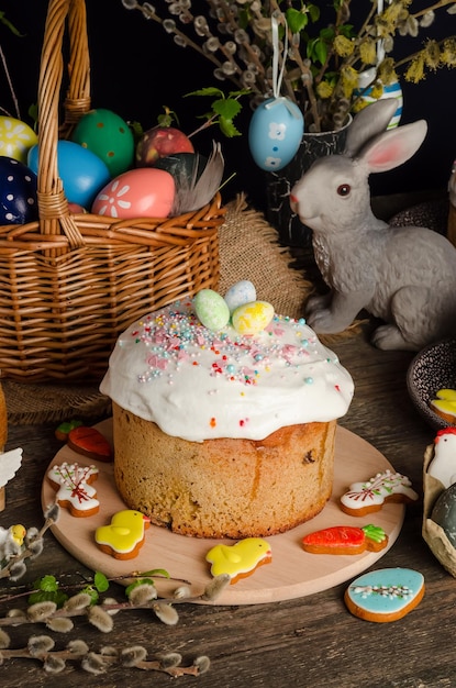 Torta pasquale e uova su una tavola festiva di pasqua con salice e una figurina di coniglio su sfondo scuro