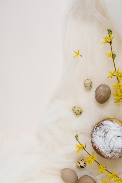 부활절 케이크는 베이지색과 패브릭 배경에 가루 설탕을 칠한 계란으로 장식되어 있습니다