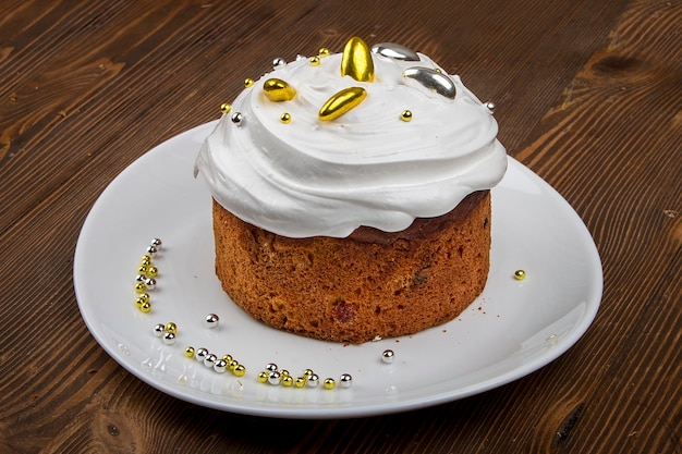 Easter cake kulich Traditional Easter sweet bread decorated meringue and candy cane shape eggs on plate on wooden table background