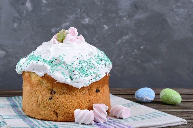 Easter cake - kulich with dried fruits, decorated with meringue on a wooden table. Sweet festive bread. Traditional Easter baking.