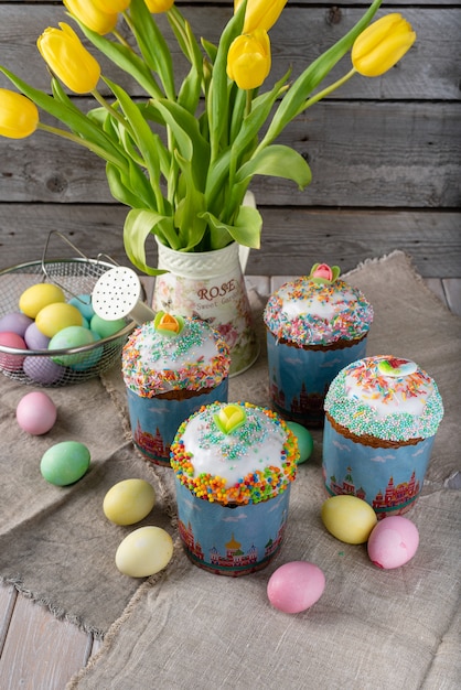 Easter cake, painted eggs with tulips on a wooden old rustic background.