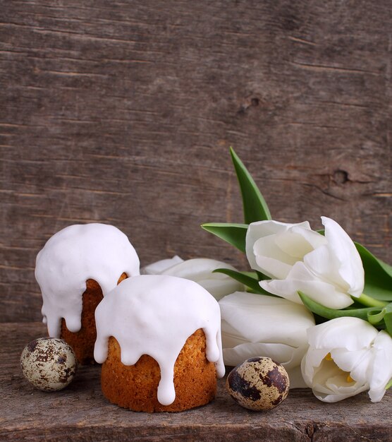 Easter cake, white tulips, quail eggs on a wooden rustic background.