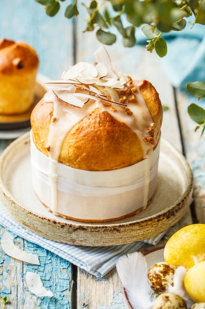 Easter cake with icing and coconut on a blue wooden table. 