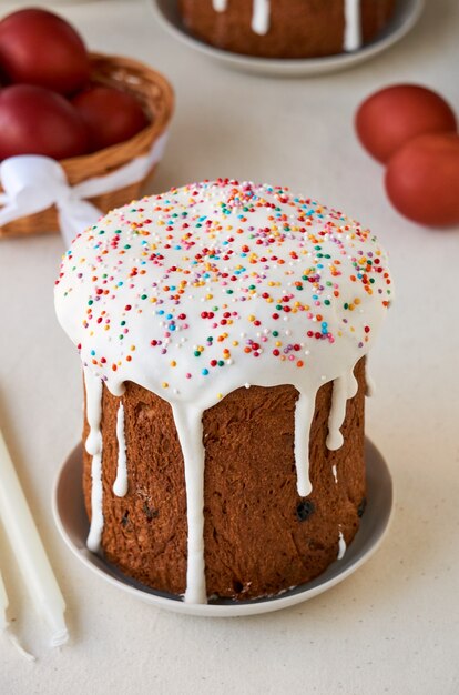 Easter cake with white icing and sweet colorful decoration on a light background