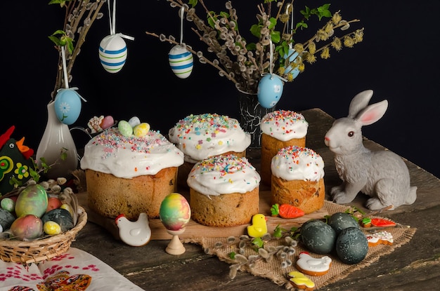 Torte pasquali e uova su una tavola festiva di pasqua con salice e una statuetta di coniglio su sfondo scuro