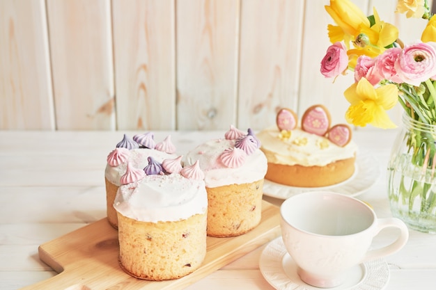테이블, 마카롱, 계란 및 꽃병에 꽃의 꽃다발에 부활절 케이크
