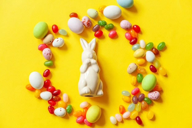 Easter candy chocolate eggs bunny and jellybean isolated on yellow background