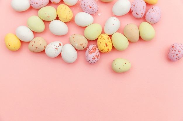 Easter candy chocolate eggs and jellybean sweets isolated on pink table