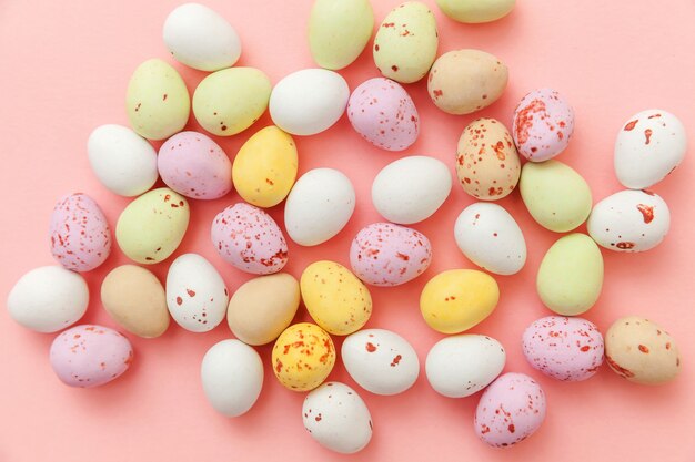 Easter candy chocolate eggs and jellybean sweets isolated on pink table