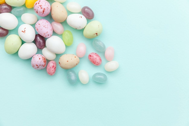 Easter candy chocolate eggs and jellybean sweets isolated on trendy pastel blue.