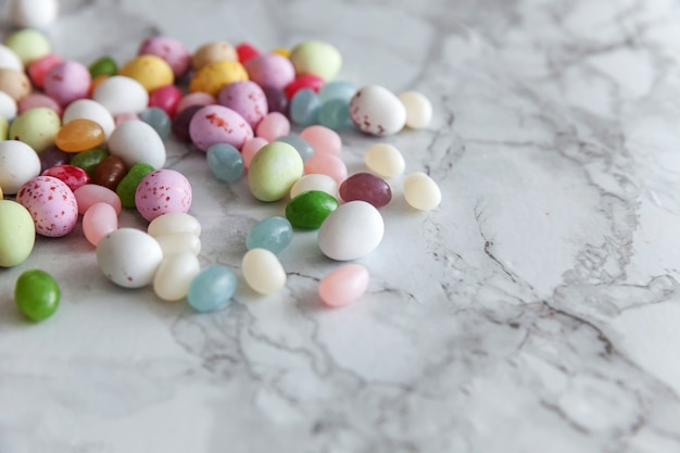 Easter candy chocolate eggs and jellybean sweets on trendy gray marble table