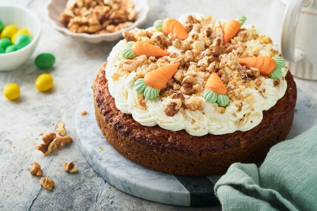 Easter Carrot cake with cream cheese frosting Delicious carrot cake with walnut and cream cheese frosting on gray concrete background table for festive dinner Traditional carrot cake Easter food