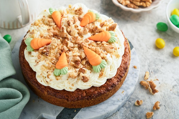 Easter Carrot cake with cream cheese frosting Delicious carrot cake with walnut and cream cheese frosting on gray concrete background table for festive dinner Traditional carrot cake Easter food