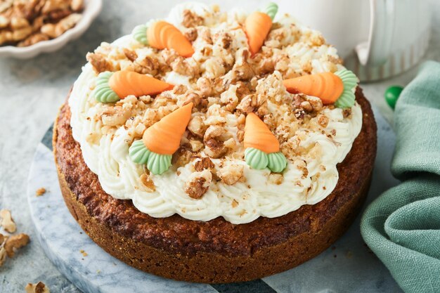 Easter Carrot cake with cream cheese frosting Delicious carrot cake with walnut and cream cheese frosting on gray concrete background table for festive dinner Traditional carrot cake Easter food