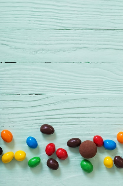 Easter chocolate eggs and candies on green wooden surface