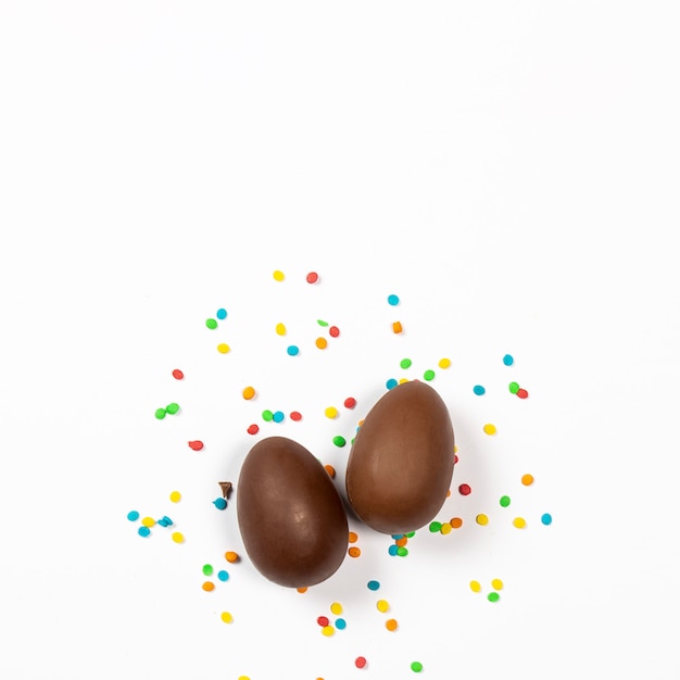 Easter chocolate eggs and colorful decorations on a light surface. Easter concept, easter treats. Square. Flat lay, top view