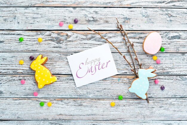 Easter colored cakes decorative eggs and sweets Greeting card On a white wooden background Top view free copying space