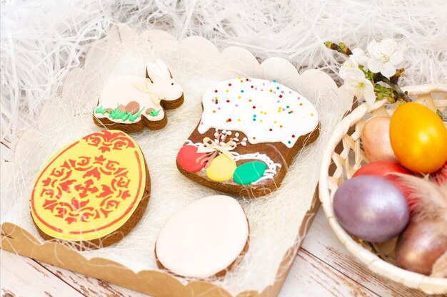 Easter Colored eggs in a basket Easter gingerbread rabbit egg Easter cake in a basket on a light wooden background