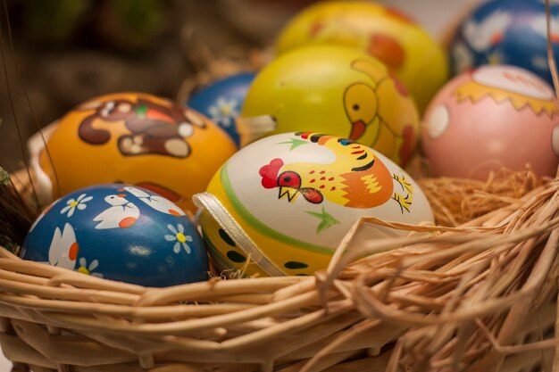 Фото Крашеные пасхальные яйца в плетеной корзине. символ пасхи.