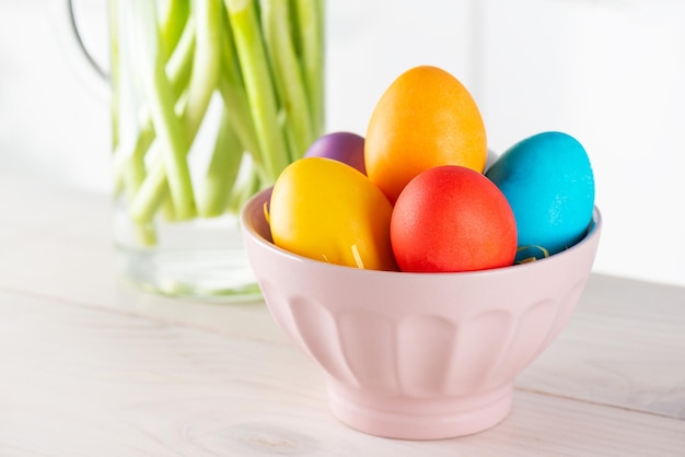 Easter colored eggs in a plate on a wooden table