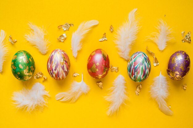 Easter colorful and bright painted eggs with white feathers and golden foil