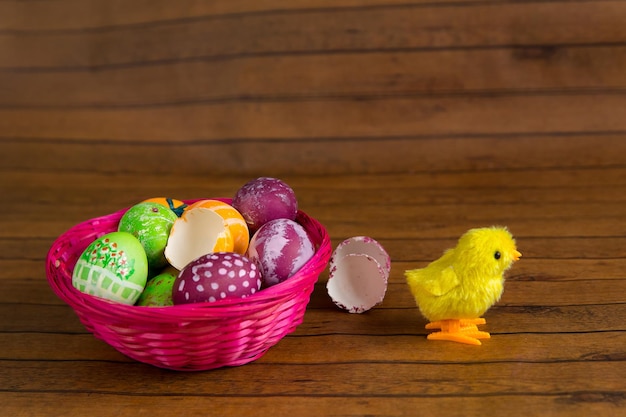 Easter colorful eggs in basket and toy chicken on wooden table Traditional religion decoration