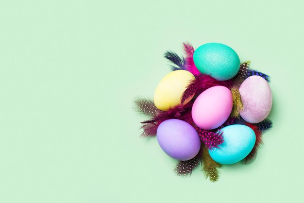 Easter colorful flat lay with feather nest on mint green background copy space top view card