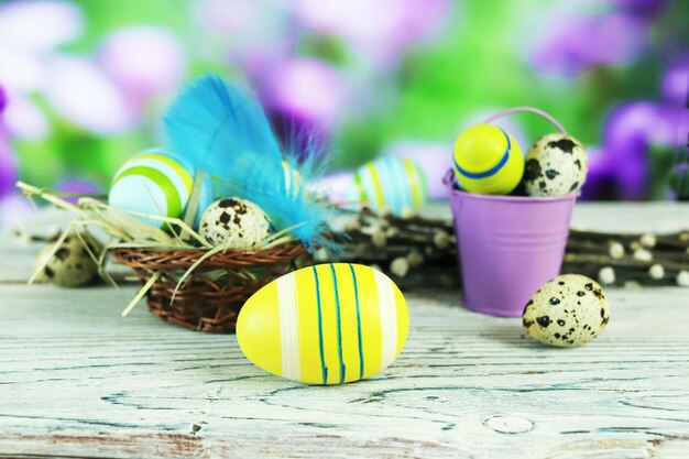 Easter composition of a basket colored eggs and feathers against the backdrop of spring nature