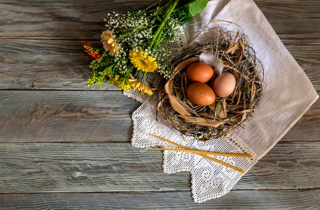 The easter composition Eggs a bouquet of colorful gerberas and church candles on wooden table closeup