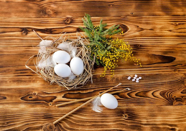 Easter composition Eggs candles and branches of a mimosa on a table closeup