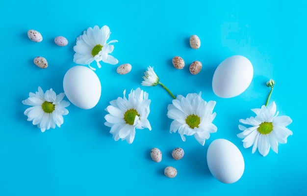 Easter composition eggs and chrysanthemum flowers on a blue background view from above