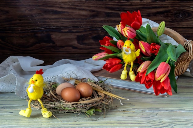 The easter composition Eggs a red tulips toys and church candles on wooden table closeup