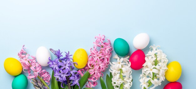 Easter composition. Multicolored easter eggs and hyacinths on blue background. Easter concept. Copy space - Image