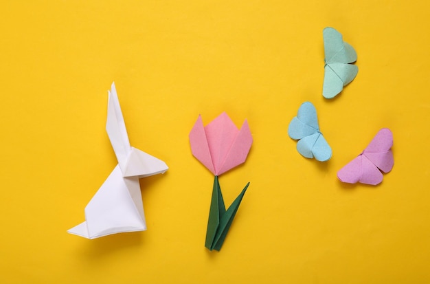 Easter composition of origami tulips rabbit and butterflies eggs on a yellow background