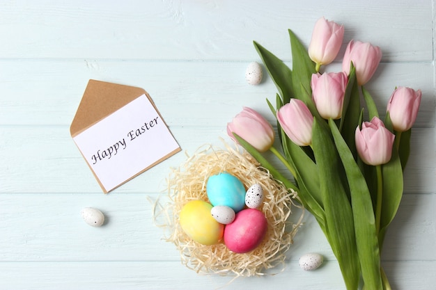 Easter composition of painted eggs and feathers on a colored background