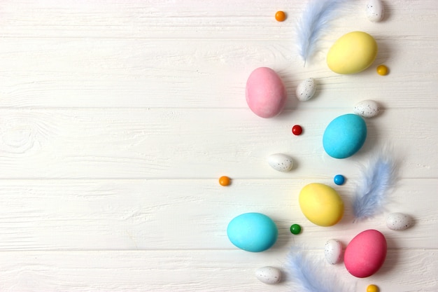 Easter composition of painted eggs and feathers on a colored background