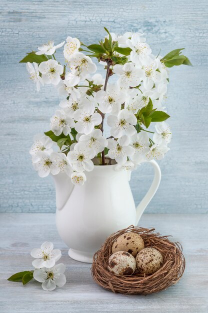 Composizione di pasqua di uova di quaglia con il bouquet di fiori di ciliegio