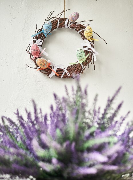 Photo easter composition on wall background, easter background with easter eggs in nest and spring flowers. copy space.