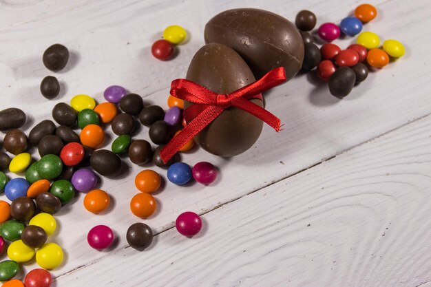 Easter composition with chocolate eggs on white wooden background