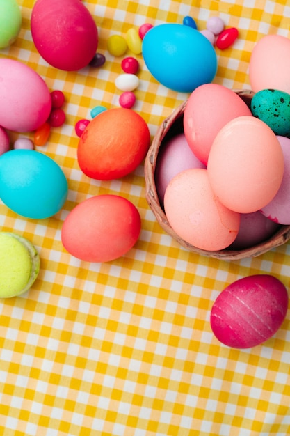 Easter composition with colored eggs and bright candies on yellow tablecloth