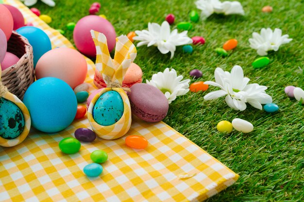 Easter composition with colored eggs and bright candies on yellow tablecloth