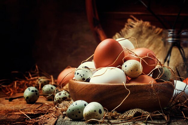 Пасхальная композиция с красочными куриными и перепелиными яйцами в деревенском стиле на винтажном деревянном фоне, селективный фокус
