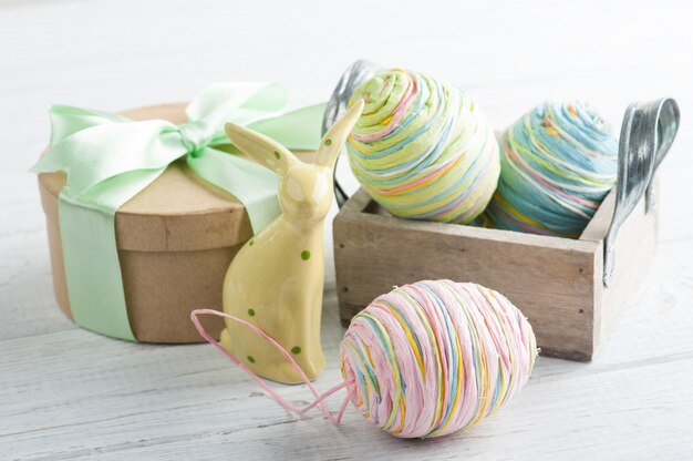 Пасхальная композиция с подарком, игрушечным кроликом и яйцами